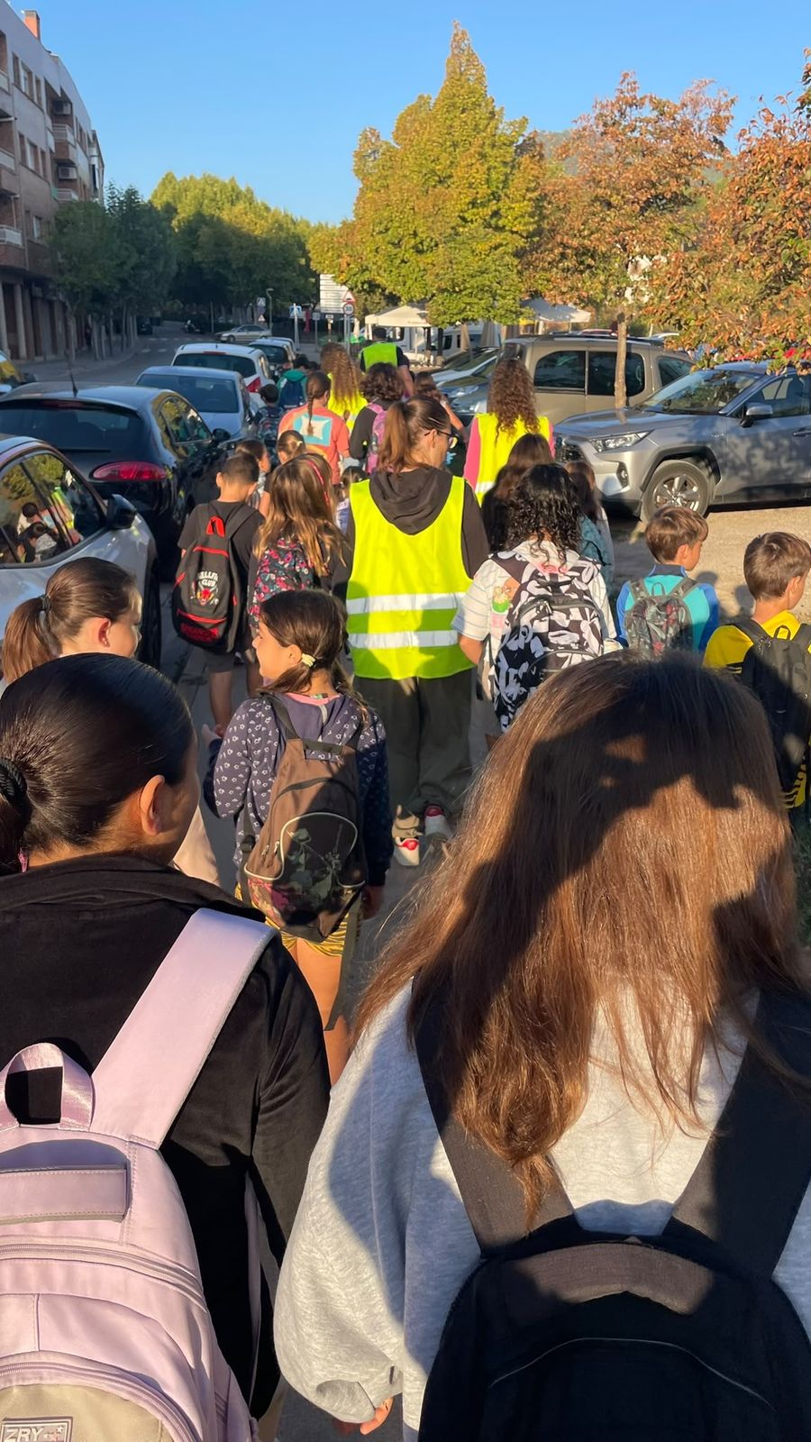 Monitores amb armilla reflectant acompanyant un grup d'infants cap a l'escola