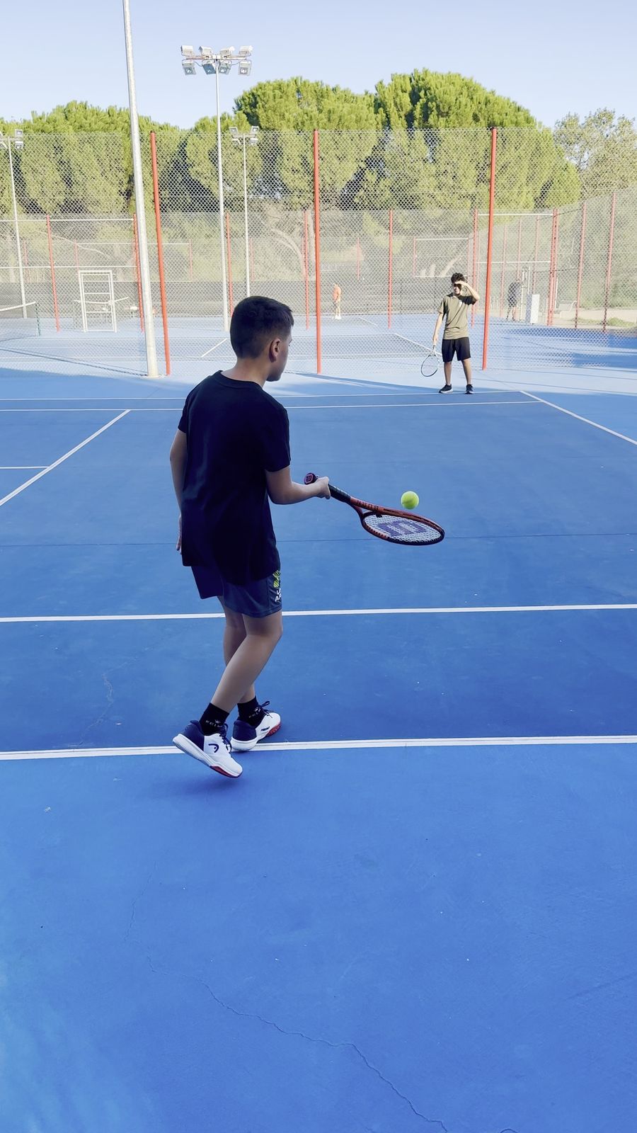 Participant del campus de tennis a punt de colpejar la pilota