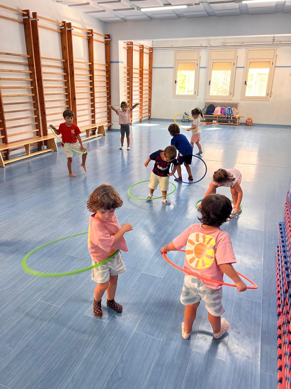 Infants petits jugant amb cèrcols al gimnàs de l'escola